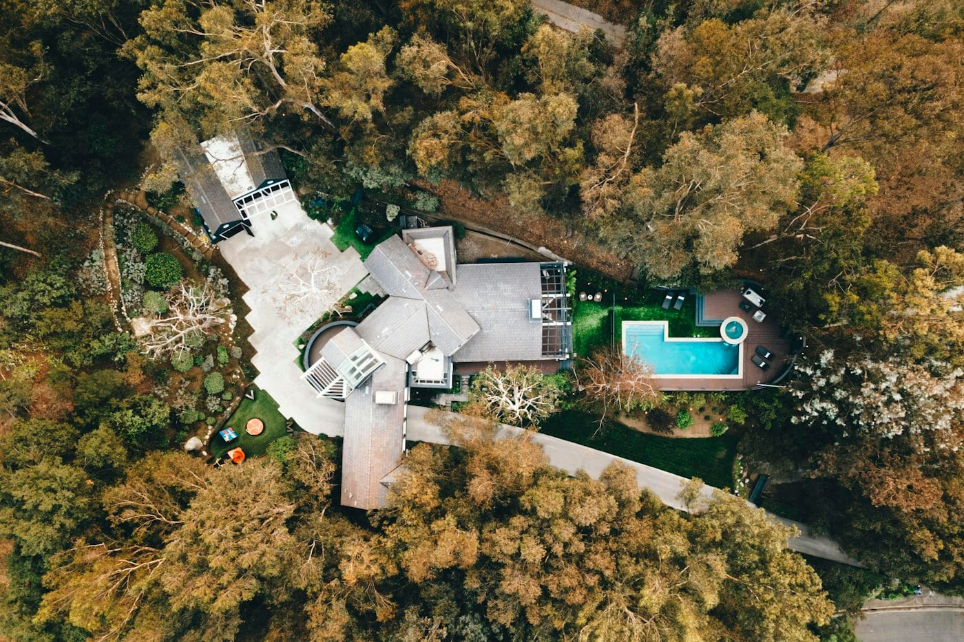 Une piscine creusée derrière une maison, entourée d’arbres