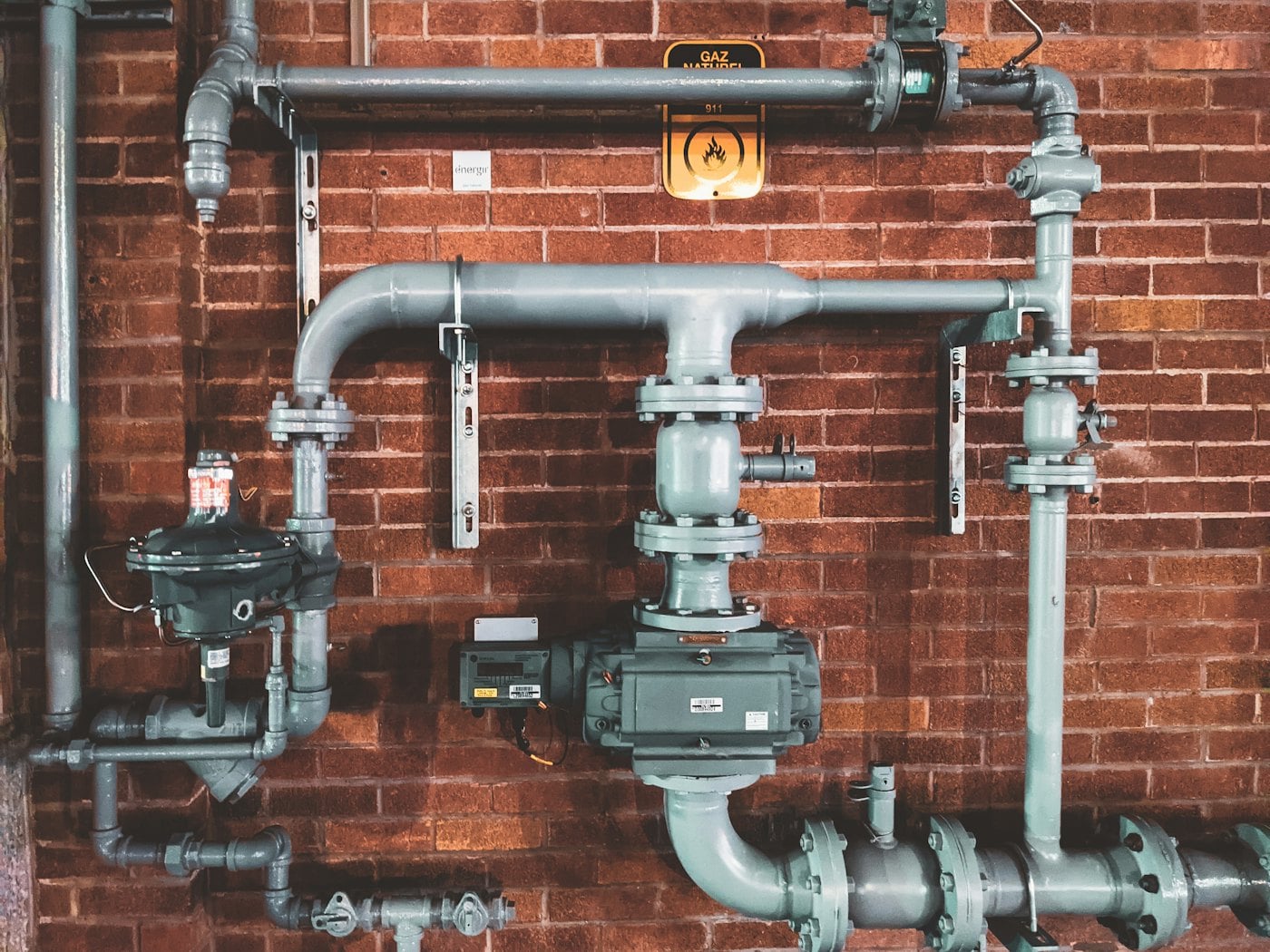 Un réseau de tuyauterie et de valves sur un mur de brique